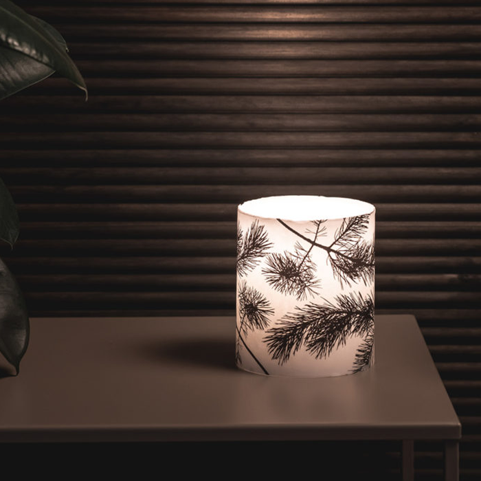 Lit Muurla Pine Large Candle on dark table