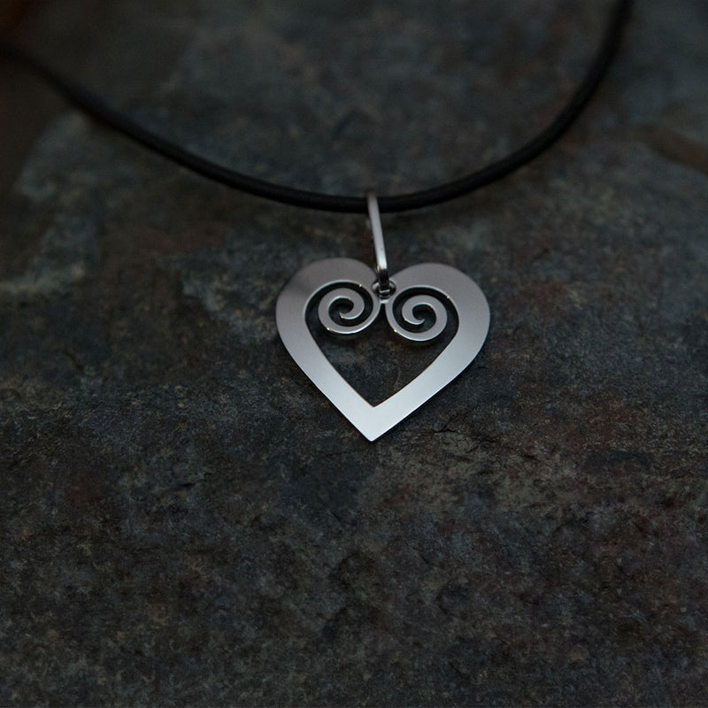 Pohjolan Helmi Curved Heart Necklace placed on rock