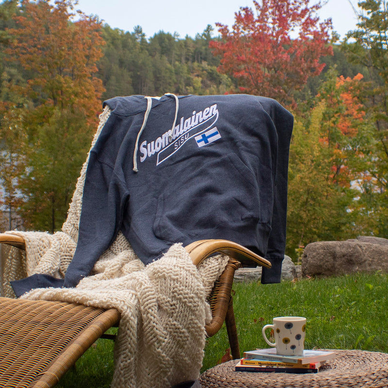 Suomalainen Heather Navy Hoodie laying on chair in yard outside