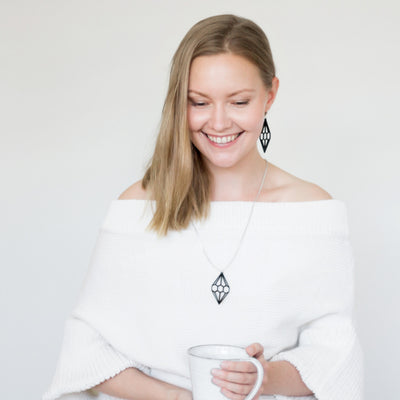 Woman wearing Valona Diamond Birch Necklace, Black and holding coffee cup