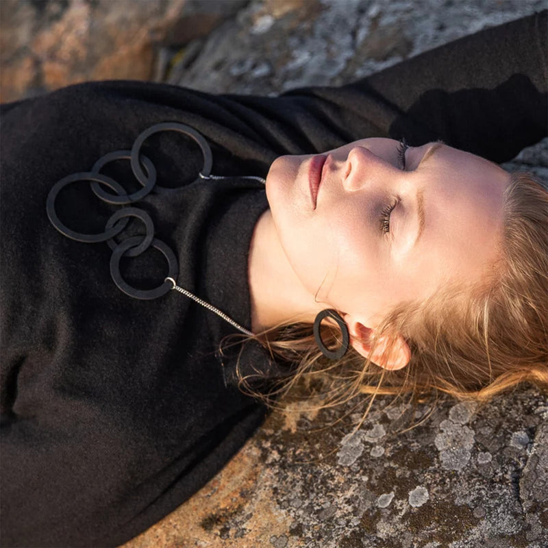 Woman laying on rocky surface wearing Valona Korona Birch Stud Earrings, Black